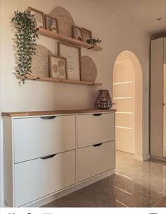 there are pictures on the wall above the cabinets in this room and below it is an arched doorway