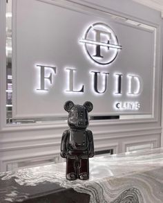 a black bear sitting on top of a table next to a sign that says fluid