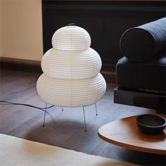 a white lamp sitting on top of a wooden table next to a black couch and chair