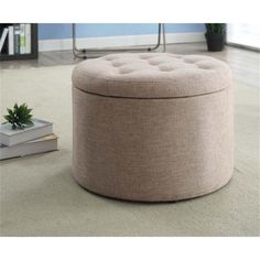 a round ottoman sitting on top of a carpeted floor next to a potted plant