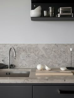 a kitchen with marble counter tops and black cabinetry, including a stainless steel sink