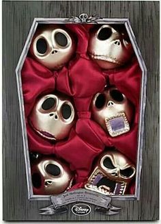 a box filled with lots of silver skulls sitting on top of a wooden floor next to a red blanket