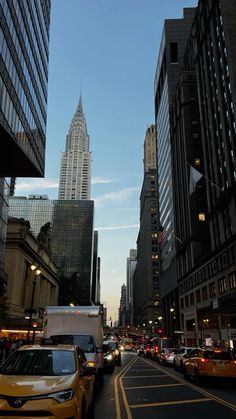 cars are driving down the street in front of tall buildings with skyscrapers on either side