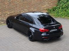 a black car parked in front of a brick wall