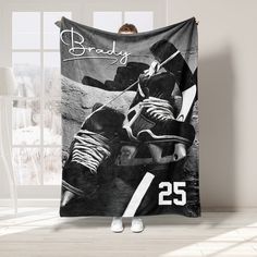 a hockey player is holding up a black and white blanket with the number 25 on it