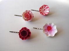 three flower bobby pins are shown on a white surface, one is pink and the other is red