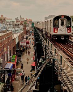 a train is coming down the tracks in an urban area with people walking on either side