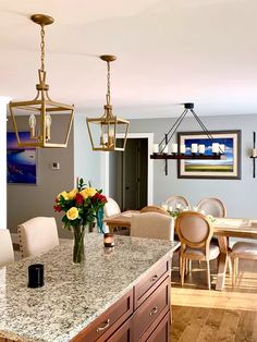 a large kitchen with marble counter tops and wooden cabinets, along with two chandeliers hanging from the ceiling