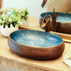 there is a blue bowl sitting on the counter in front of two mirrors and a vase with flowers