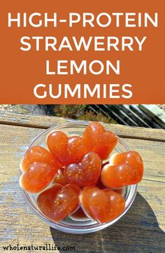 a glass bowl filled with fruit sitting on top of a wooden table next to a sign that says high protein strawberry lemon gummies