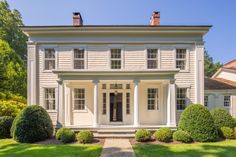 a large white house sitting on top of a lush green field