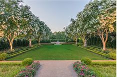 a large garden with lots of trees and flowers in the middle of it, surrounded by hedges