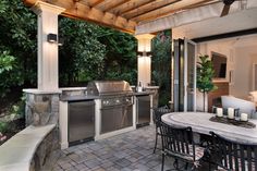 an outdoor kitchen and dining area with grill