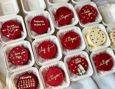 there are many red and white cupcakes in the plastic containers with writing on them