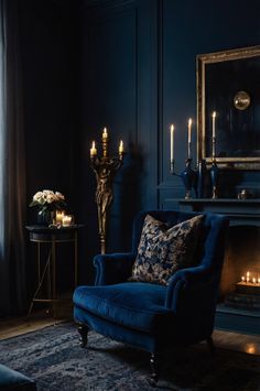 a living room with dark blue walls and candles on the fireplace mantels in front of it