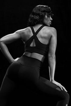 a woman in black sports bra and leggings with her back to the camera