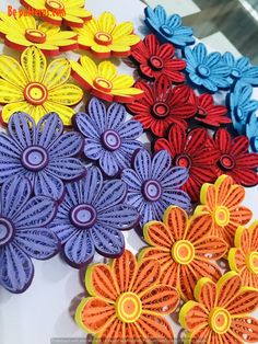 several different colored flowers sitting on top of a white table with yellow and red petals