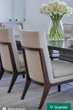 a dining room table with four chairs and a vase filled with flowers on the table