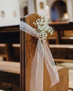 a bouquet of baby's breath sitting on top of a wooden pew in a church