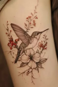 a hummingbird sitting on top of a branch with flowers in it's beak