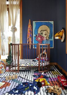 a baby crib in the corner of a room with blue walls and artwork on the wall