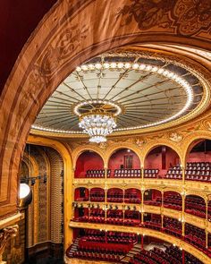 an ornately decorated auditorium with chandelier and red seats