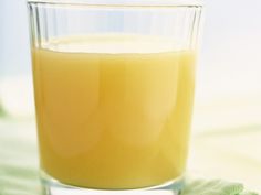 a glass filled with orange juice sitting on top of a green cloth next to a napkin