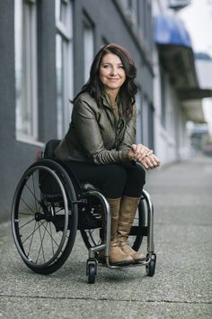 a woman sitting in a wheel chair on the side of a building with her legs crossed