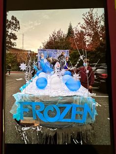 a frozen birthday cake with frosting and decorations on the top is displayed in front of a group of people