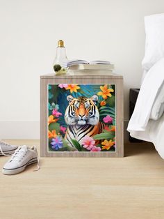 a painting of a tiger surrounded by flowers on a night stand next to a bed