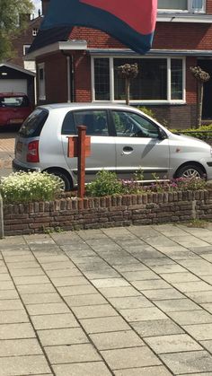 a car parked in front of a house with a flag on it's roof