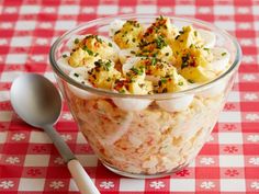 a glass bowl filled with food on top of a red and white checkered table cloth