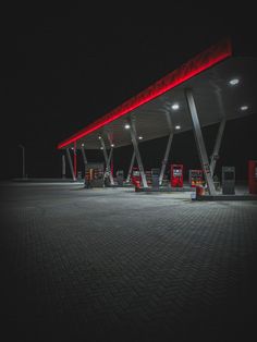 an empty gas station at night with red lights