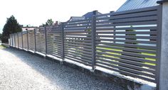 a long metal fence next to a gravel road