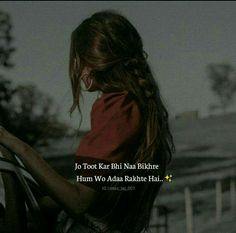 a girl with long hair standing in front of a fence and looking down at the ground