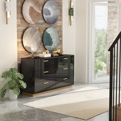 a living room filled with furniture next to a stair case and wall mounted art on the wall