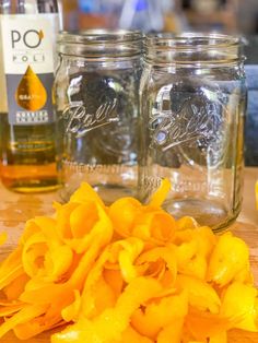 three mason jars filled with macaroni and cheese sitting on top of a wooden cutting board