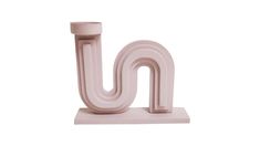 a pink letter that is on top of a white stand with a small object in the middle