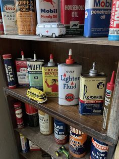 many different types of tins on a shelf in a room with other paint cans