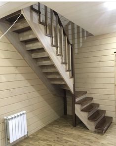 an empty room with wooden floors and stairs leading up to the second floor, next to a radiator