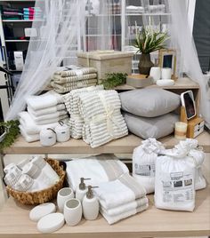 towels and other items are on display in a room with sheer curtains, plants, and baskets