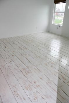 an empty room with white walls and wood floors