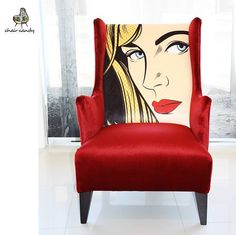 a red chair sitting in front of a window with a painting on it's back