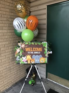 a welcome to the jungle sign in front of a building with balloons hanging from it