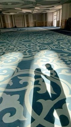 the shadow of a person standing in front of a large blue and white floor tile