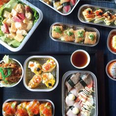 there are many different types of sushi in the trays on the blue table