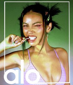 a woman brushing her teeth in front of a green background with the word alo above it