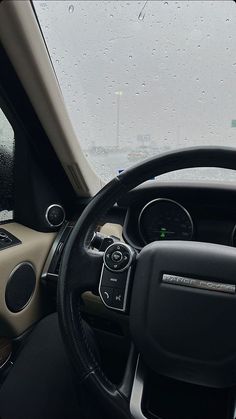 the interior of a vehicle with rain drops on the windshield and steering wheel, along with dashboard controls