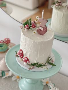 a white cake sitting on top of a table next to two donuts and a mirror