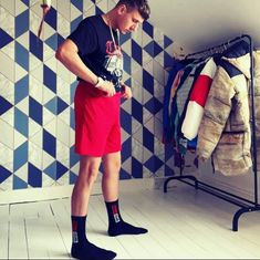 a young man standing in front of a rack with clothes hanging on it's hooks